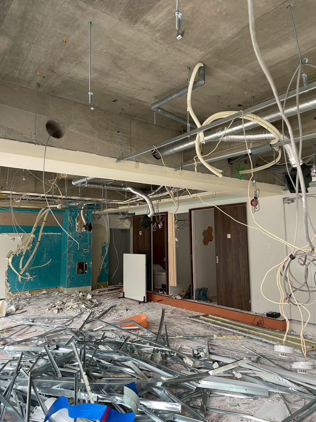 天井設備が露出した商業テナント内で軽量鉄骨と廃材が集積している施工中の様子
