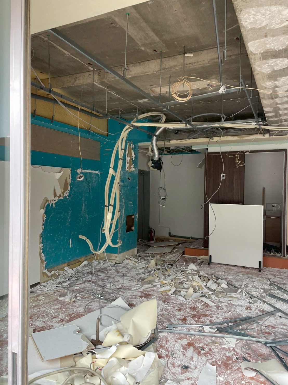 石膏ボードやクロス撤去後の壁面と天井配線が確認できる学習塾テナントの解体現場